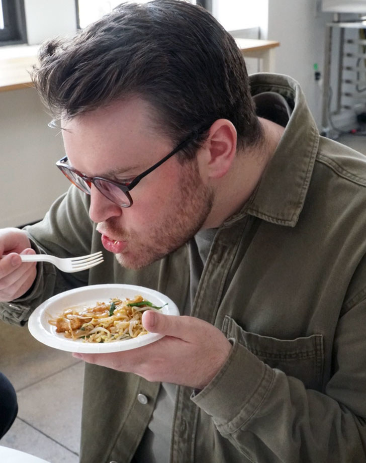 A man eating pad Thai with vegetables
