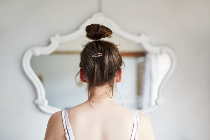 View from behind of a woman looking her reflection in the mirror