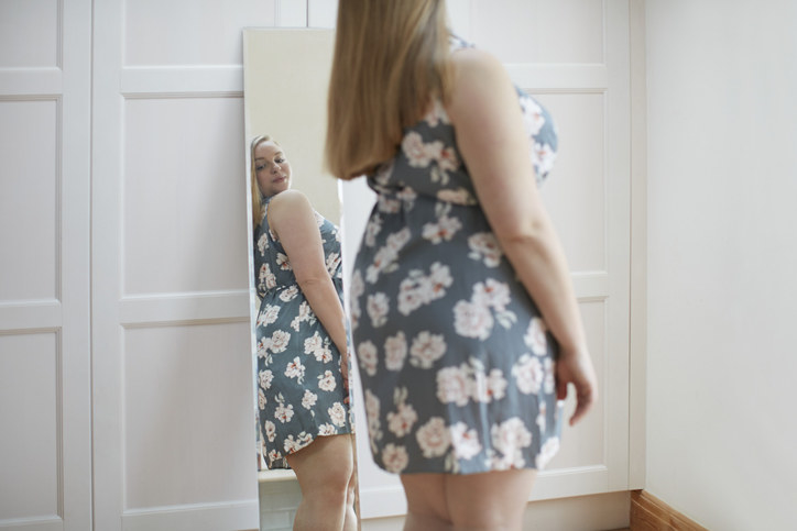 a young woman looking at reflection in mirror