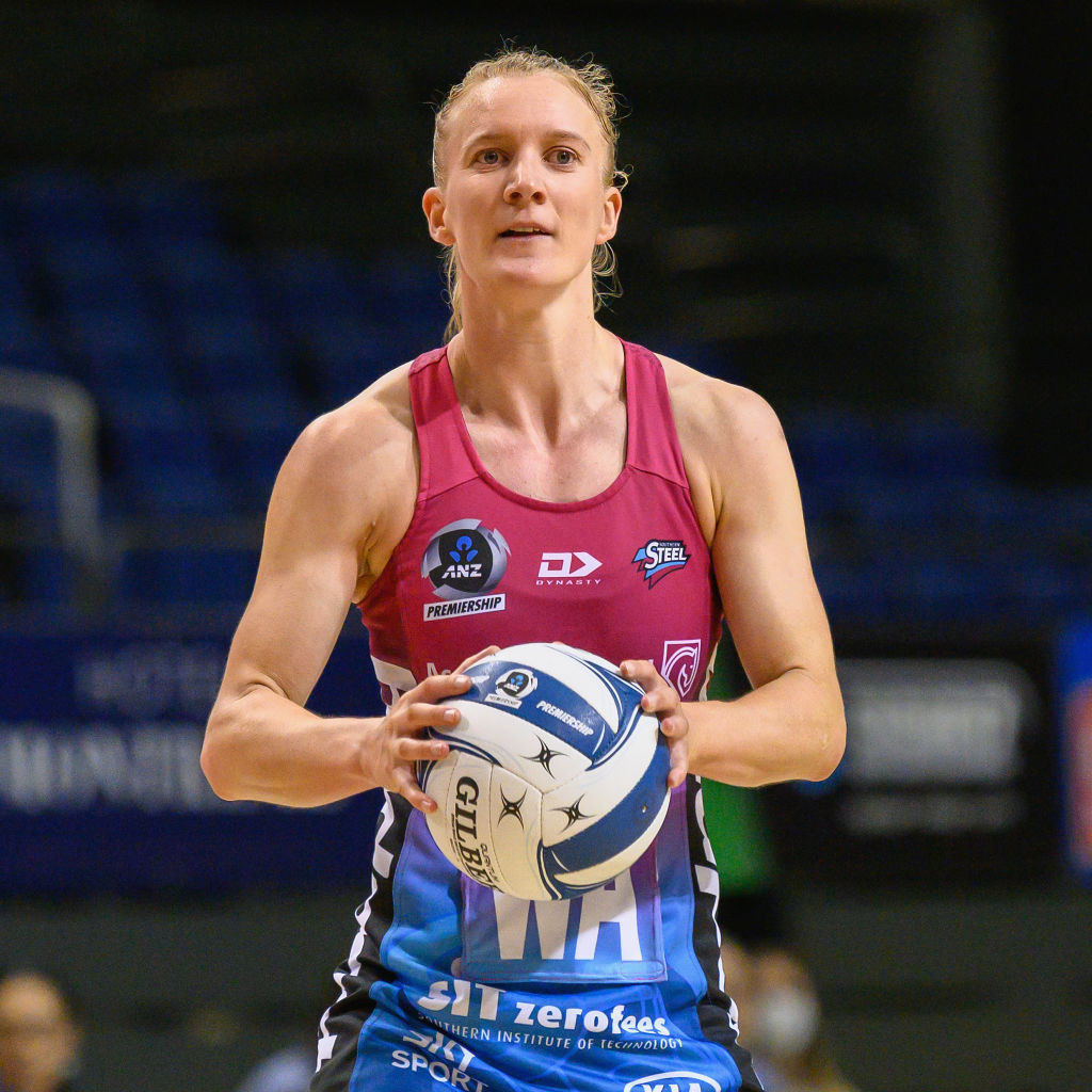 A professional netball player holds a netball, which is about the size of a soccer ball