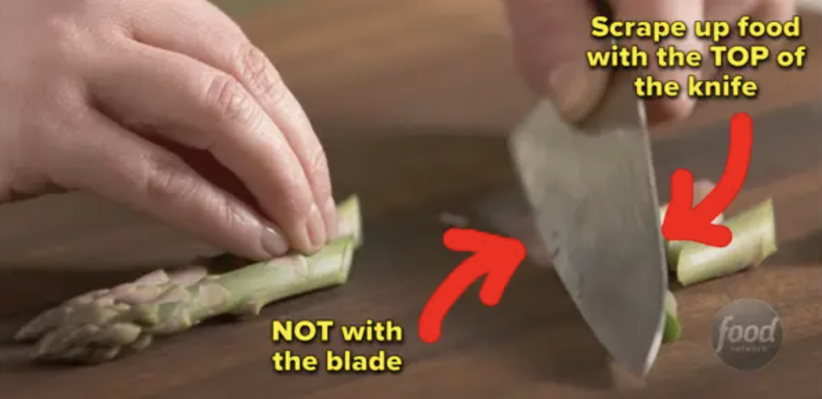 Someone chopping asparagus with captions to scrape up food with the TOP of the knife, not with the blade