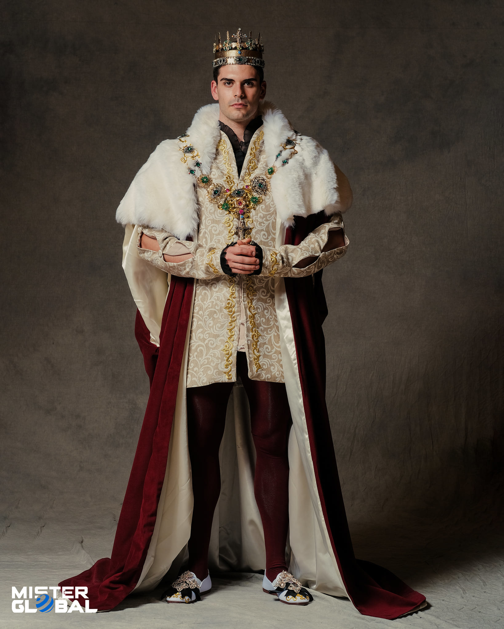 Man wearing a crown, long robe, ornate jacket, and tights