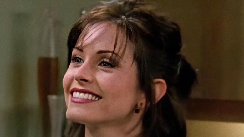 A close up of Monica Geller as she smiles brightly