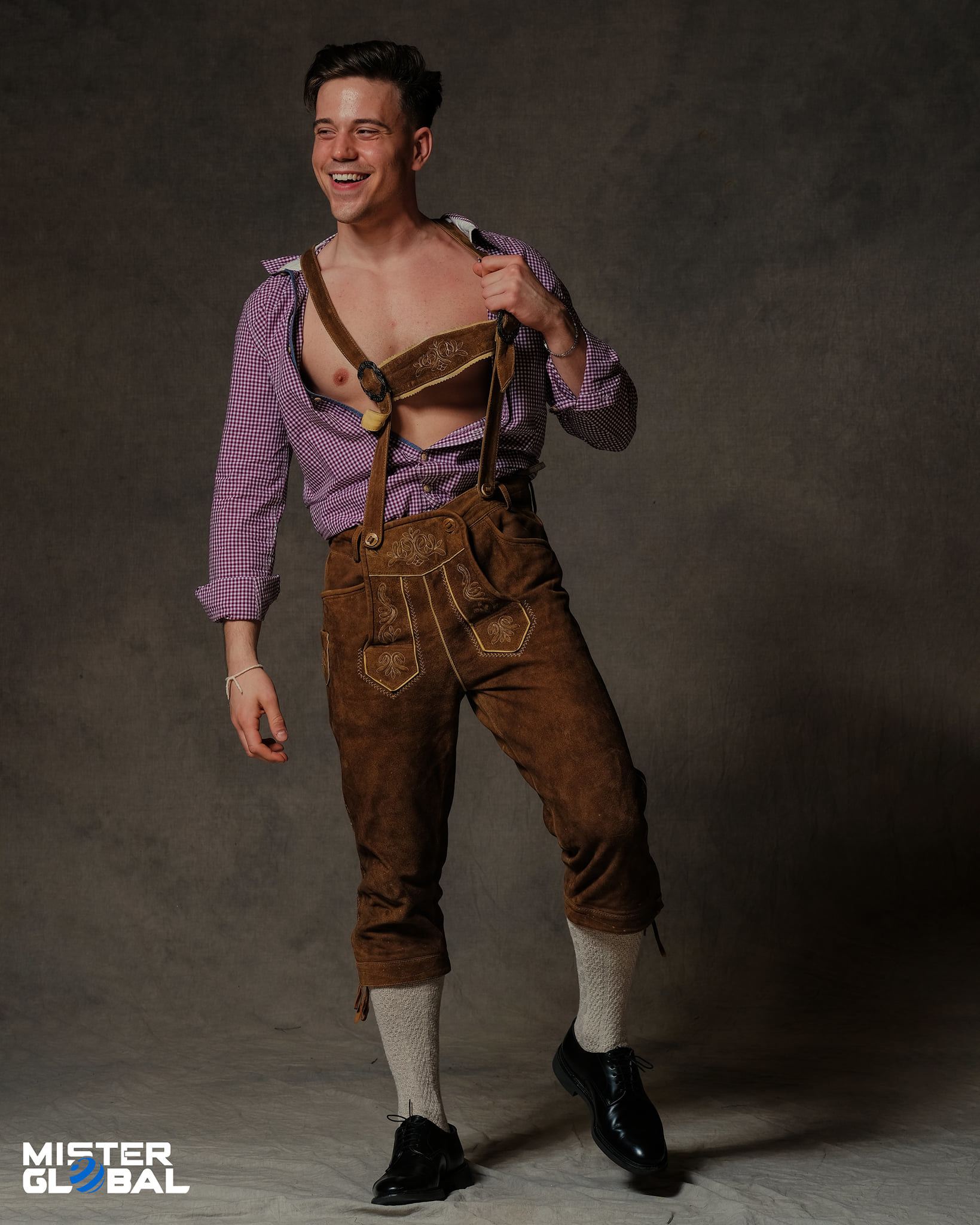 Smiling man in knee-length overalls with suspenders, open shirt, and long socks