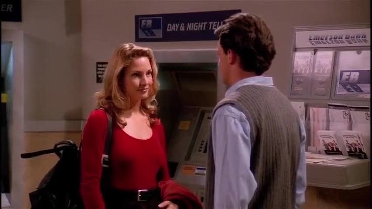 Jill Goodacre stands in front of Chandler Bing wearing a brightly colored sweater