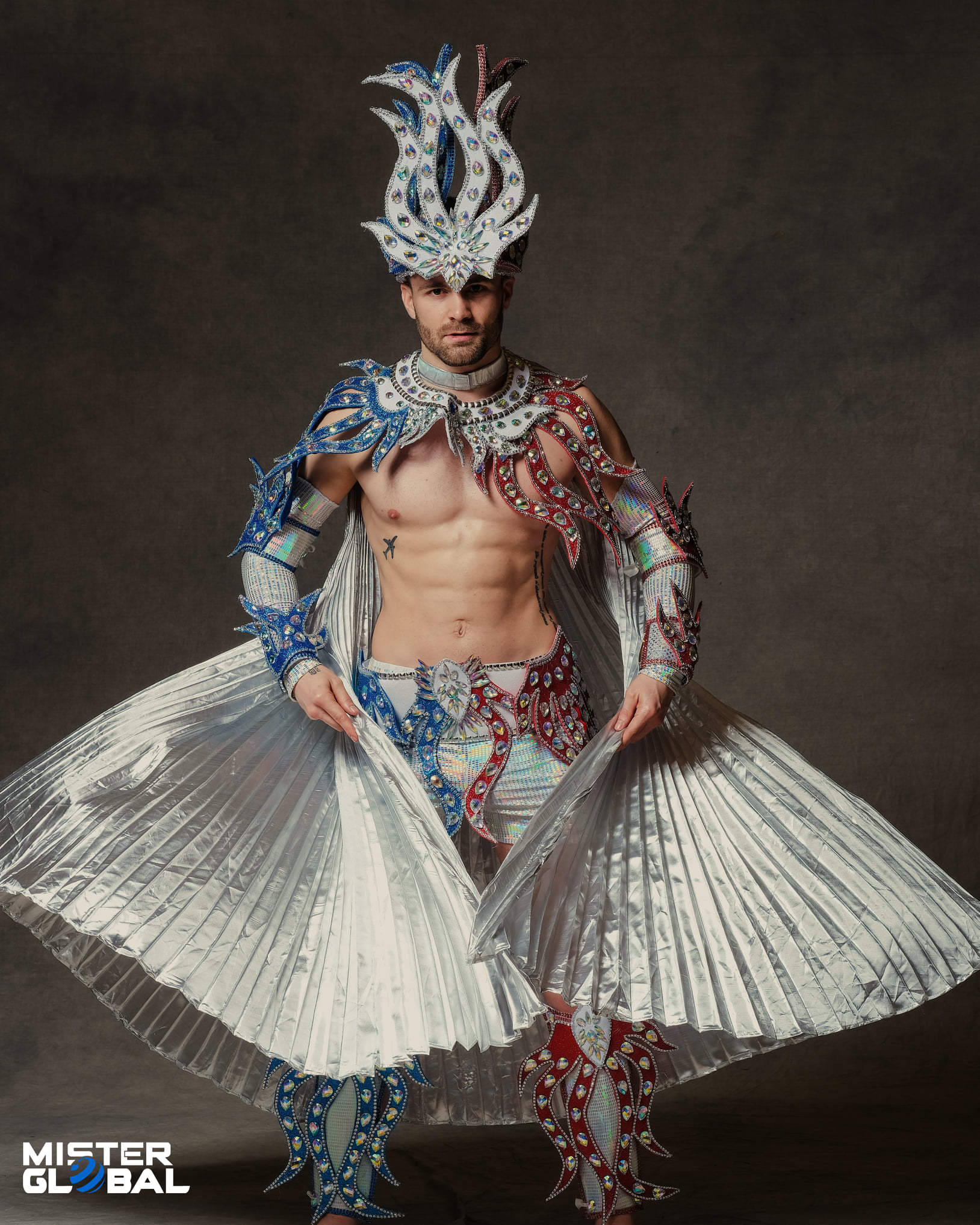 Man with dramatic headdress and chest-baring costume with flowing, accordion flaps