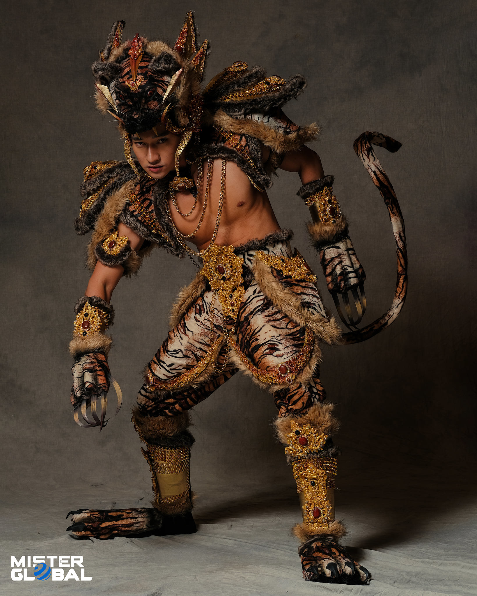 A bare-chested man wearing a dramatic headdress and an outfit with animal patterns and talons