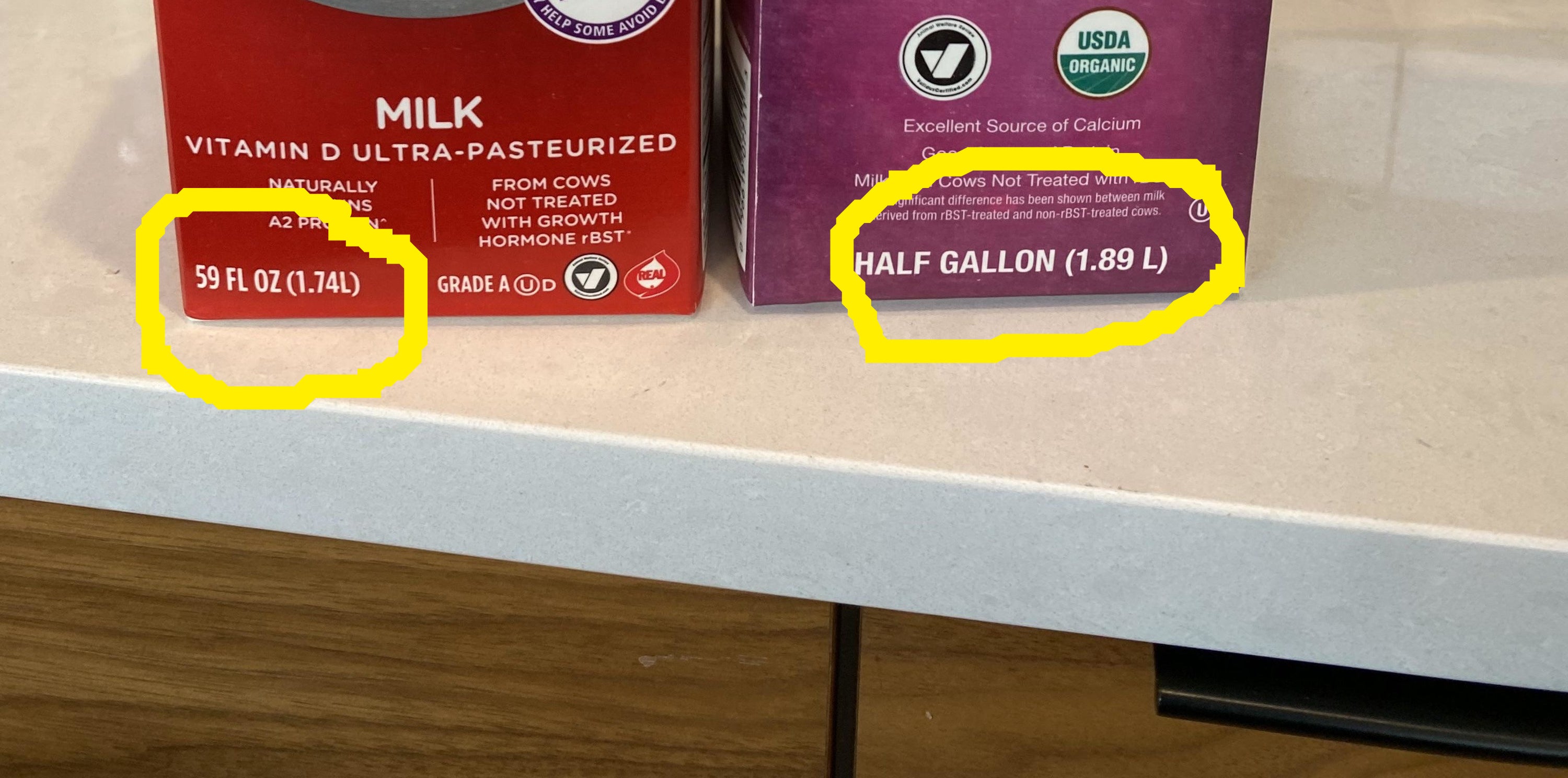 Close-up showing one milk carton has about a 10th of a liter less milk than a half gallon