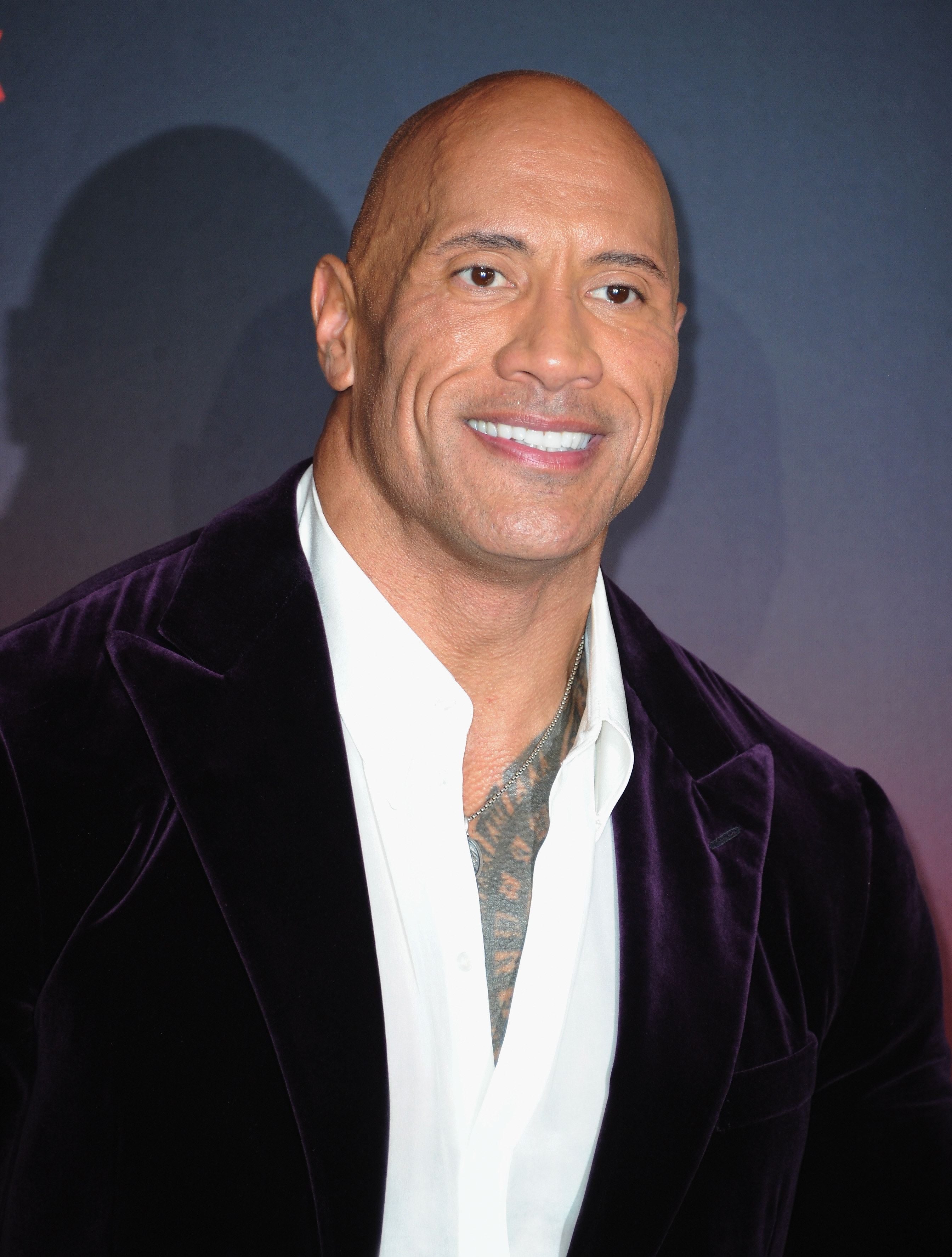 Dwayne Johnson smiles while wearing a suit
