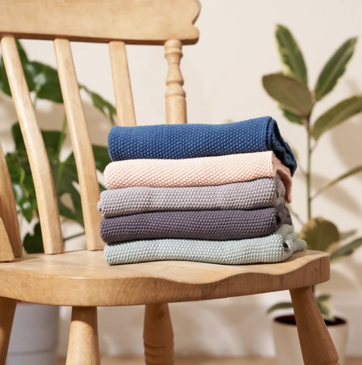 A stack of five cotton hand towels in different colors on a chair