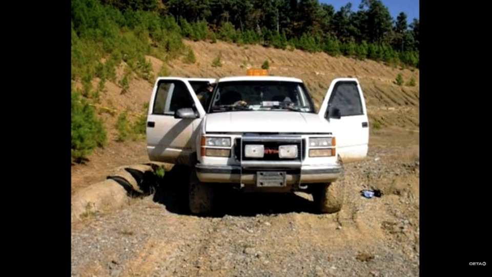 A white pickup truck with the doors open on a dirt road