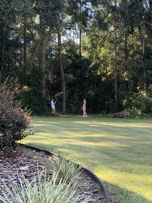 A view of the same woman&#x27;s photoshoot from further away, revealing she&#x27;s just in her backyard
