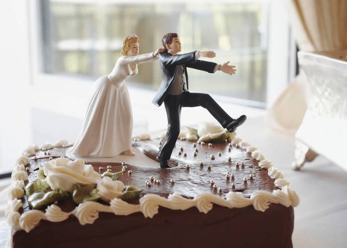 A bride wedding cake topper pulls the groom topper backwards by his collar as he tries to run away