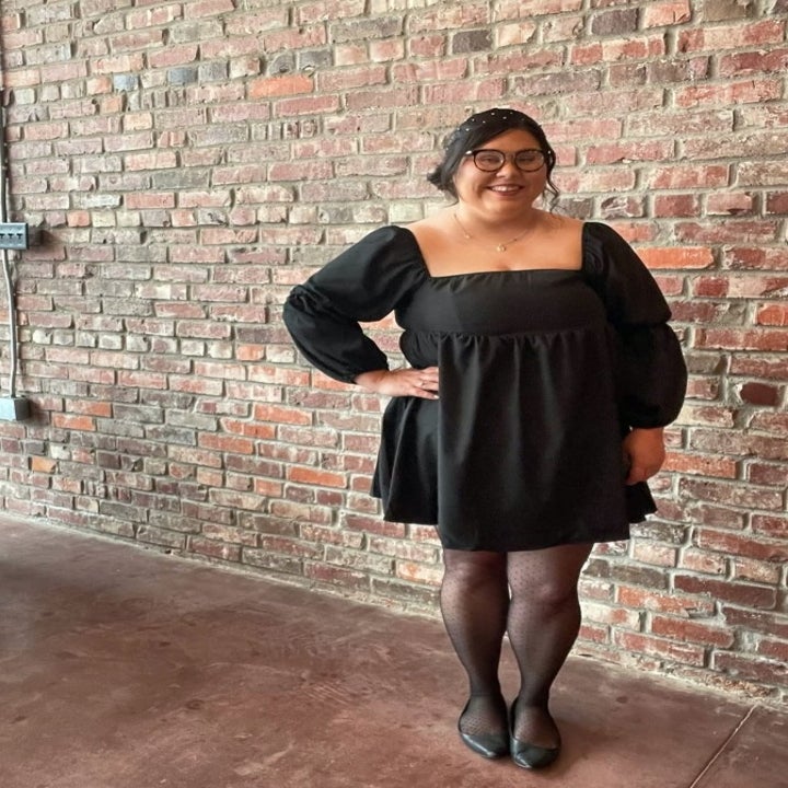 A reviewer wearing a black square neck puff sleeve mini dress