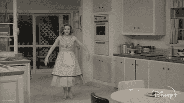 a gif of elizabeth olsen in wandavision magically opening all her kitchen cupboards