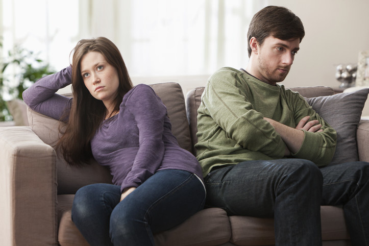 Couple facing away from each other on the sofa