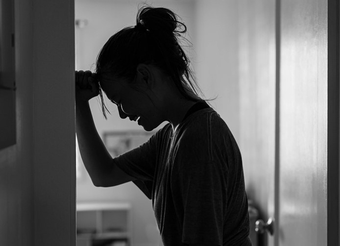 Person crying against a wall