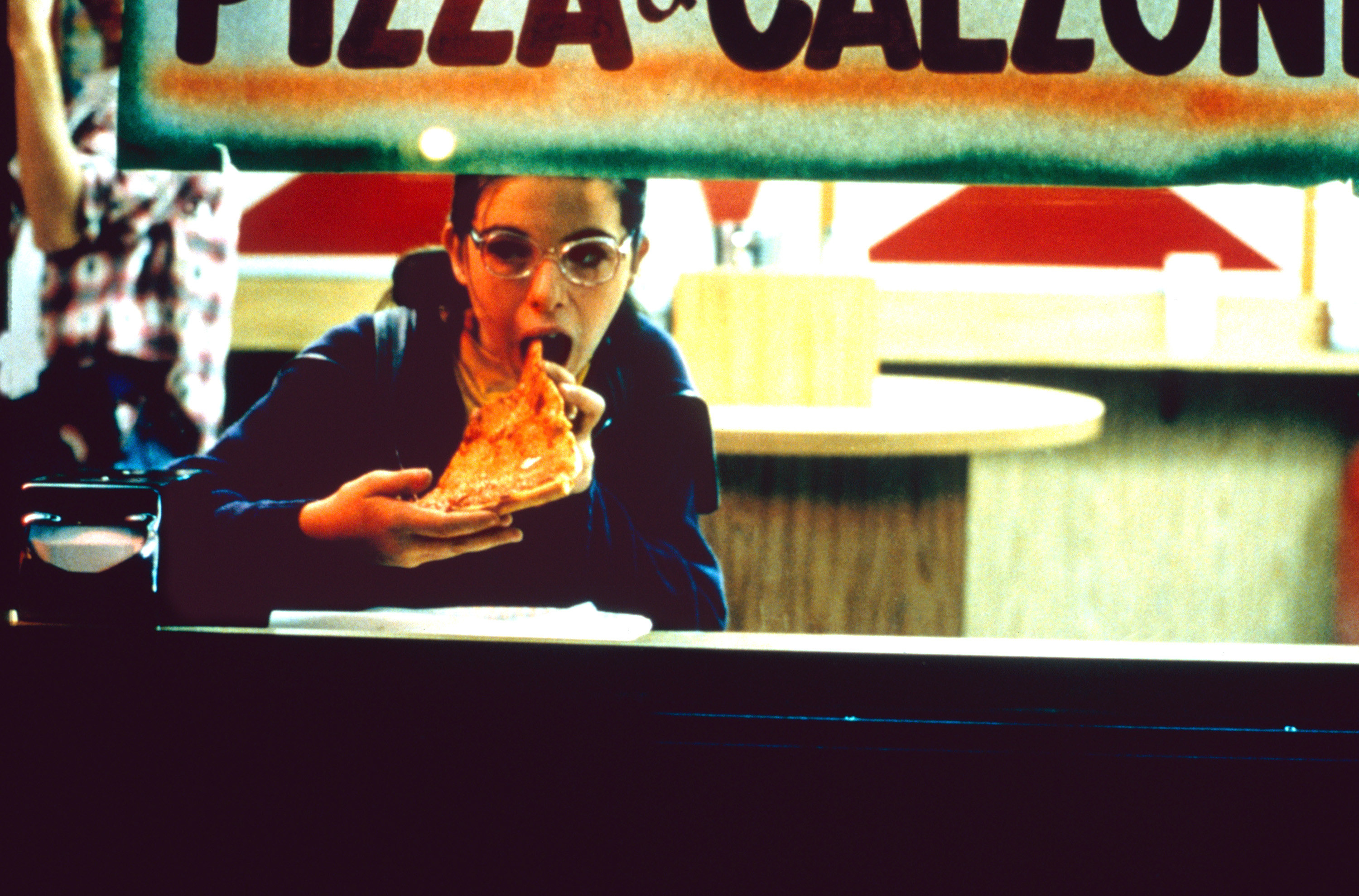 一个十几岁的女孩独自吃一块比萨饼