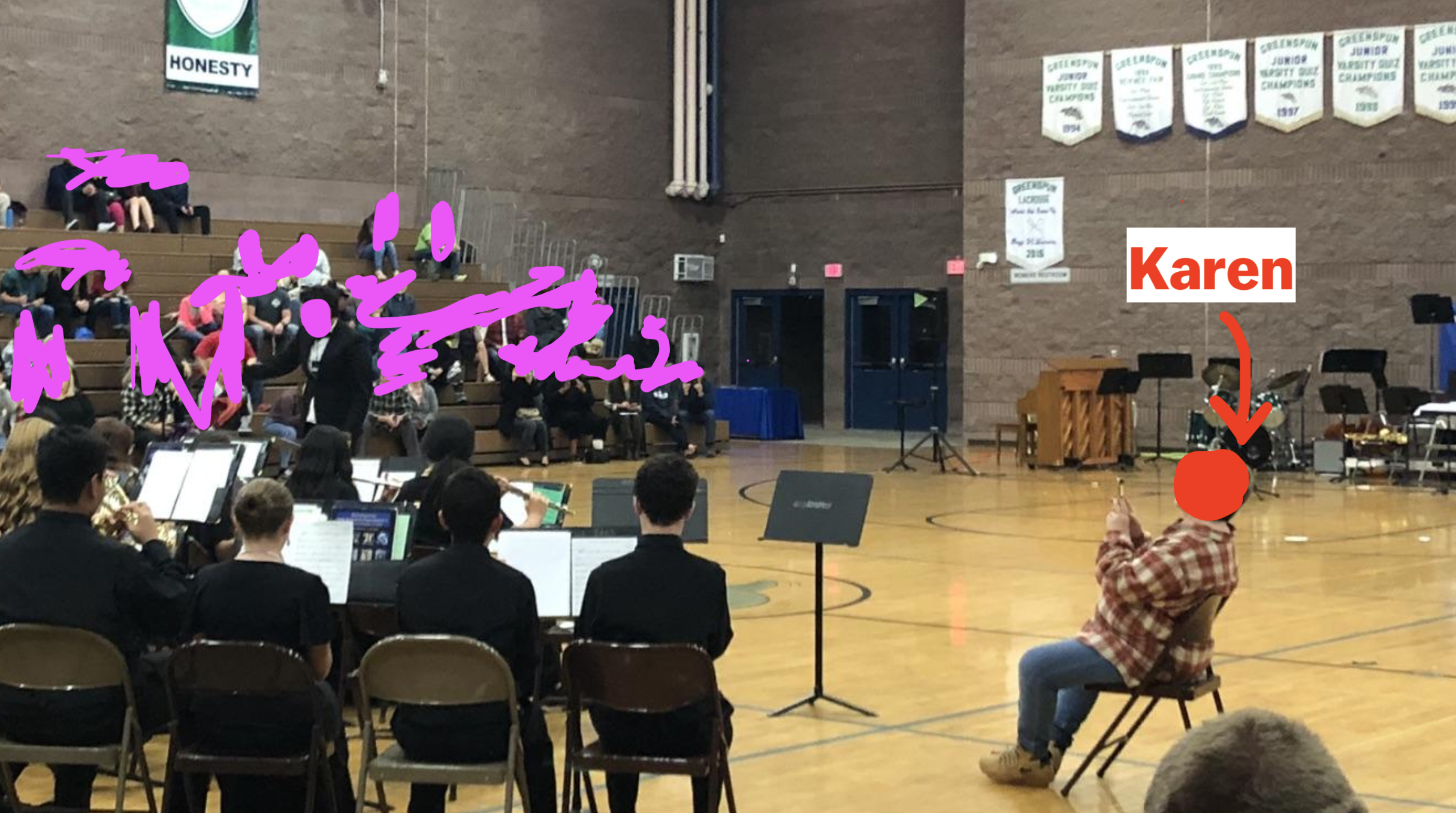 women taking photos of her kid performing in school band from a few feet away in the middle of the gym