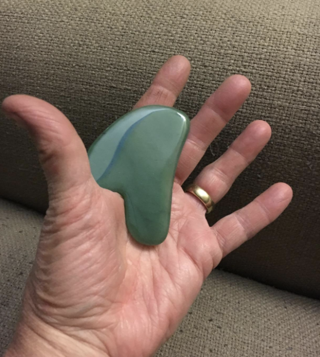 a reviewer photo of a hand holding the gua sha tool