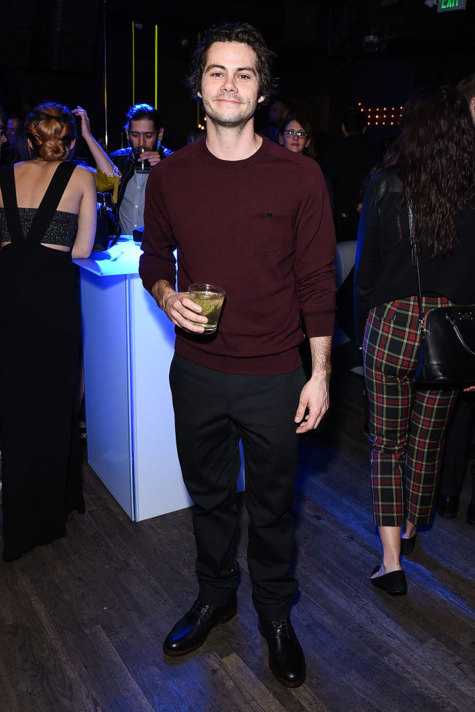 Dylan smiling for a picture as he holds a drink at an event