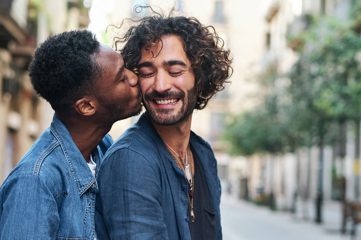 Queer couple kissing and smiling
