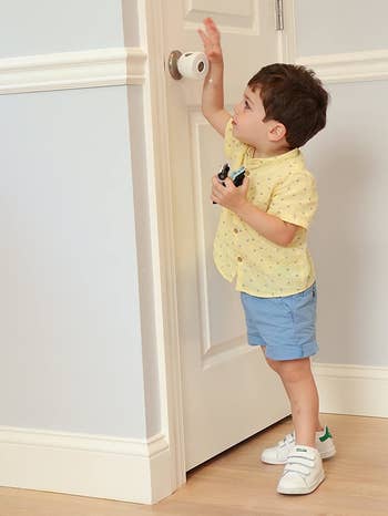 A child trying to open a door knob that has a cover installed on it