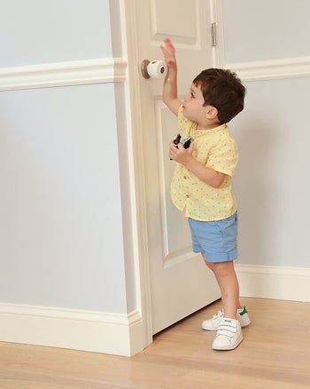 A child trying to open a door knob that has a cover installed on it