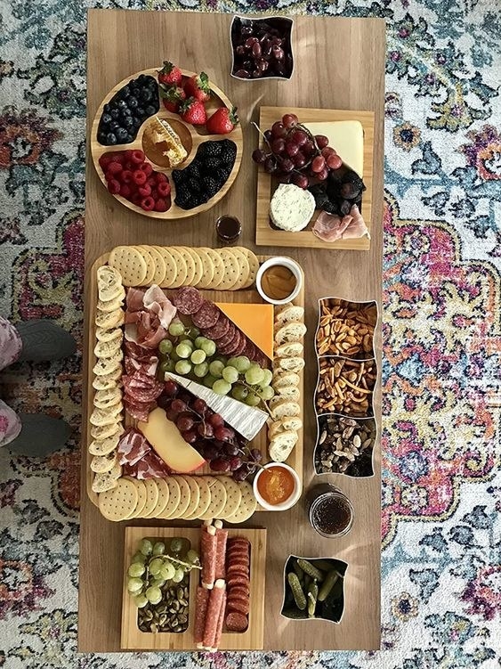 A cheese board covered with meat, cheese, crackers, and fruit