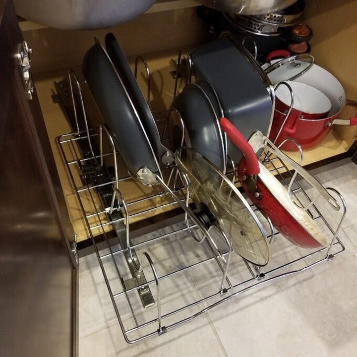 the silver pot organizing rack with lids and pans in another cabinet