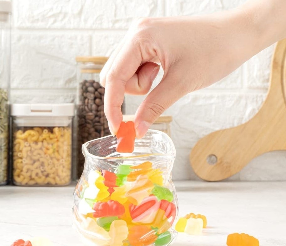 A person reaching into the glass bowl to pull a piece of candy out