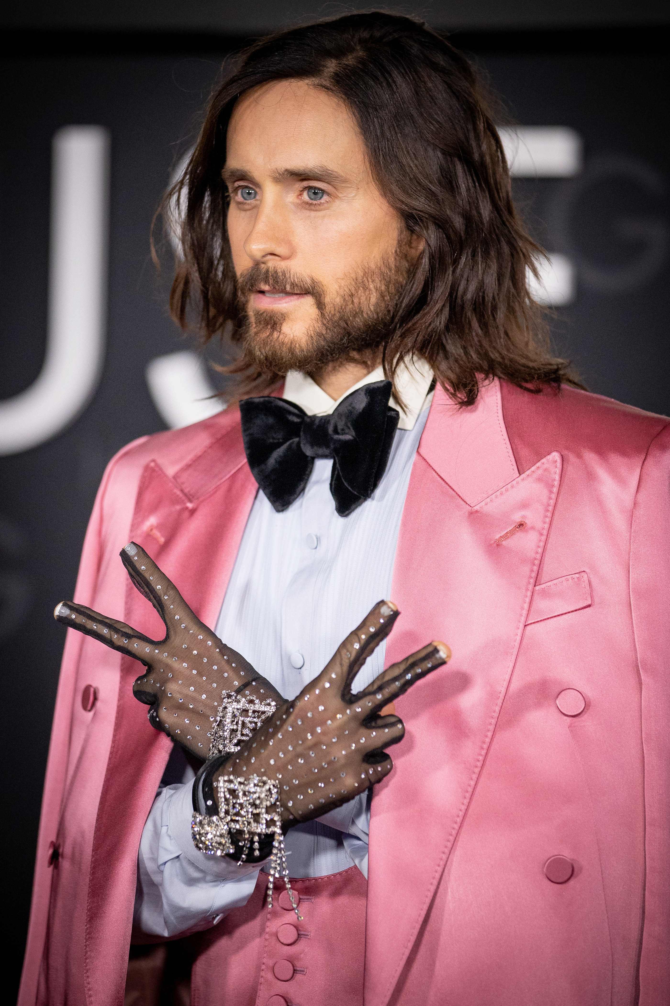 Leto puts up peace signs while wearing see-through gloves that are bedazzled