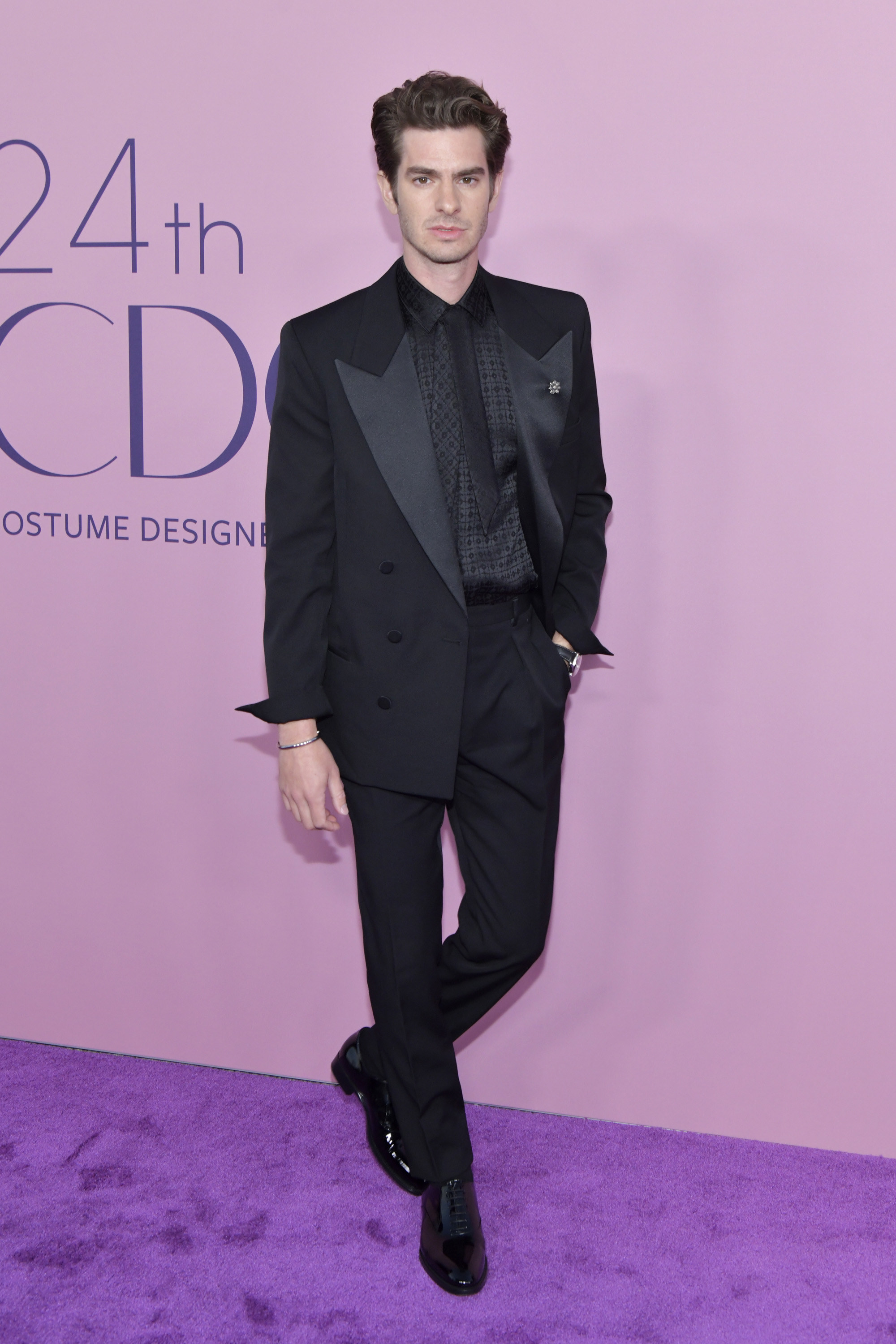 Andrew wears a black suit with wide silk lapels
