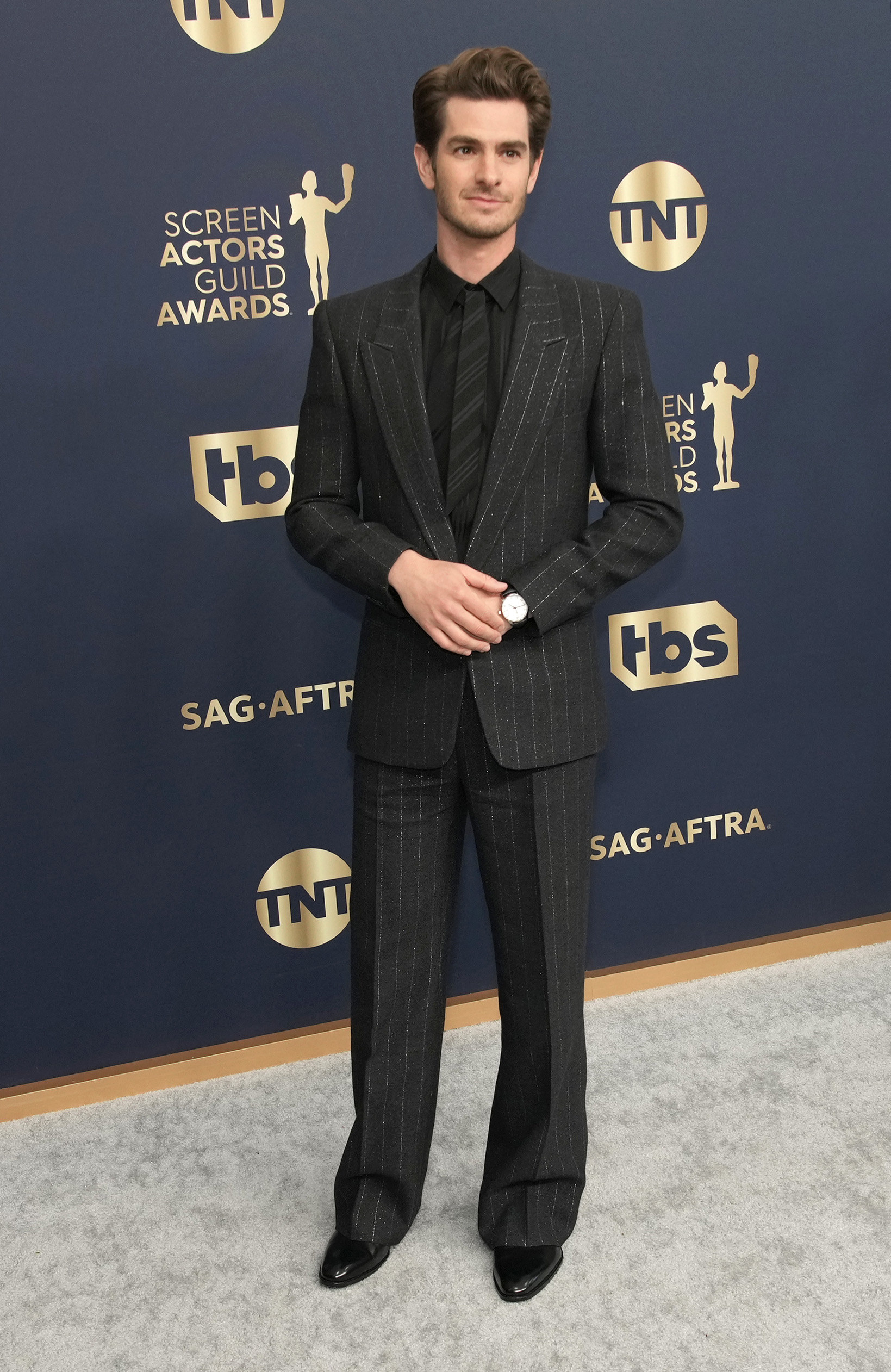 Andrew wears a pinstripe suit with wide leg pants