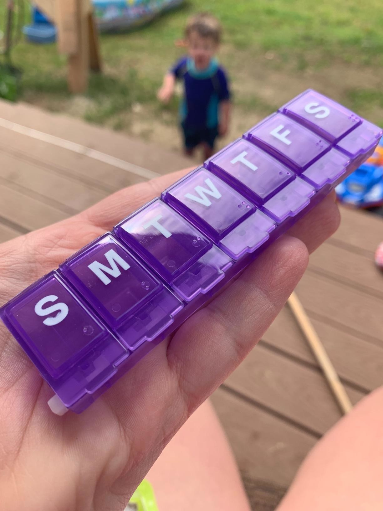 reviewer's photo of them holding the purple box with a child in the background