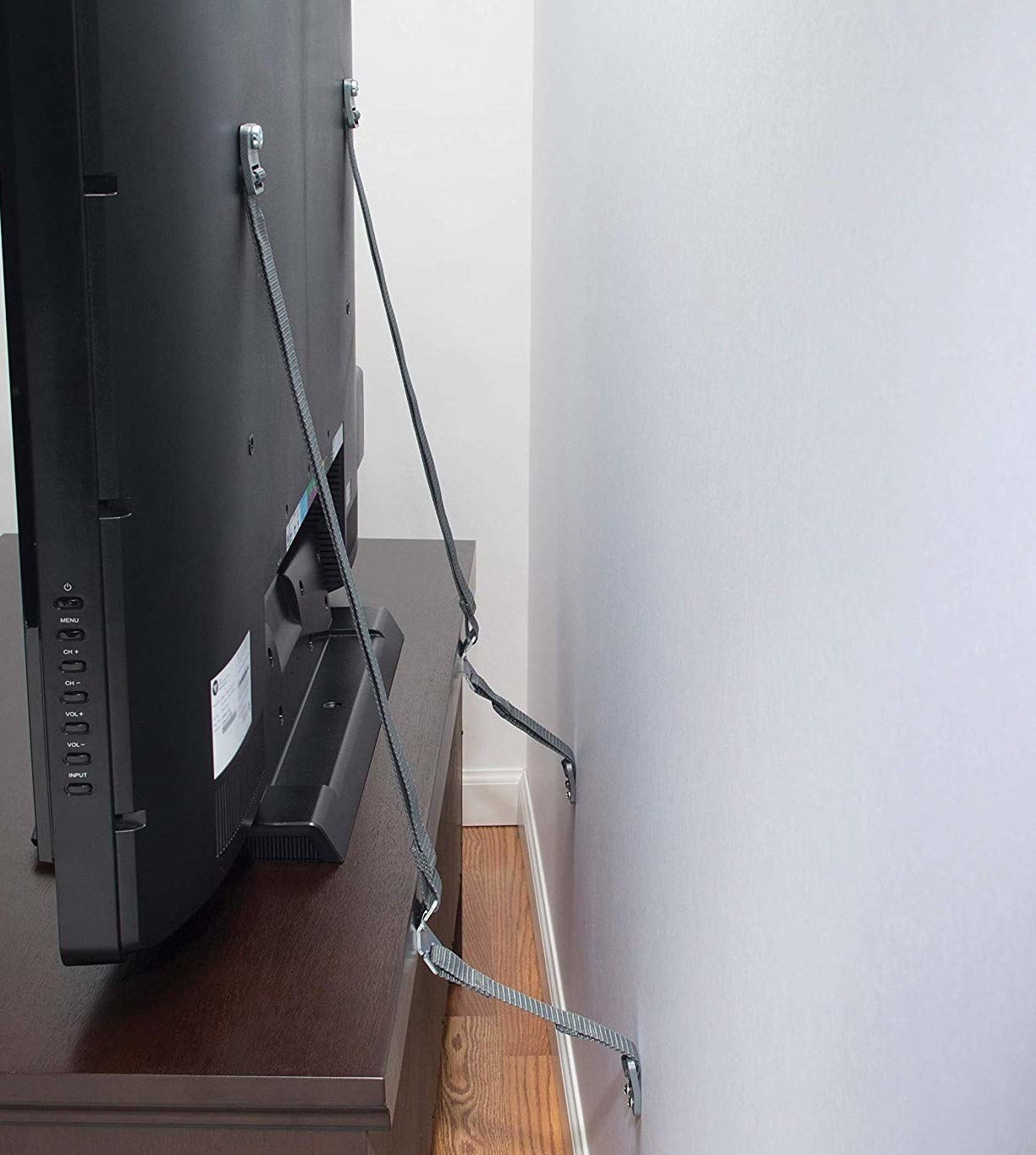 A pair of safety straps securing the TV to the wall