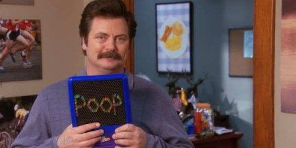 a man holding a colorful sign that says "poop"