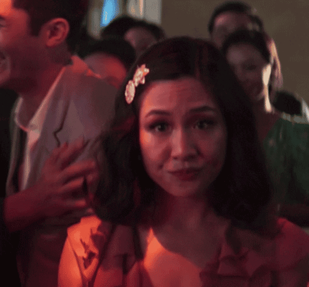 gif of someone walking through a crowd showing their hand and pointing to their engagement ring
