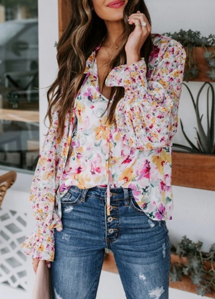 A model wearing a boho yellow/pink floral flowy long sleeve blouse