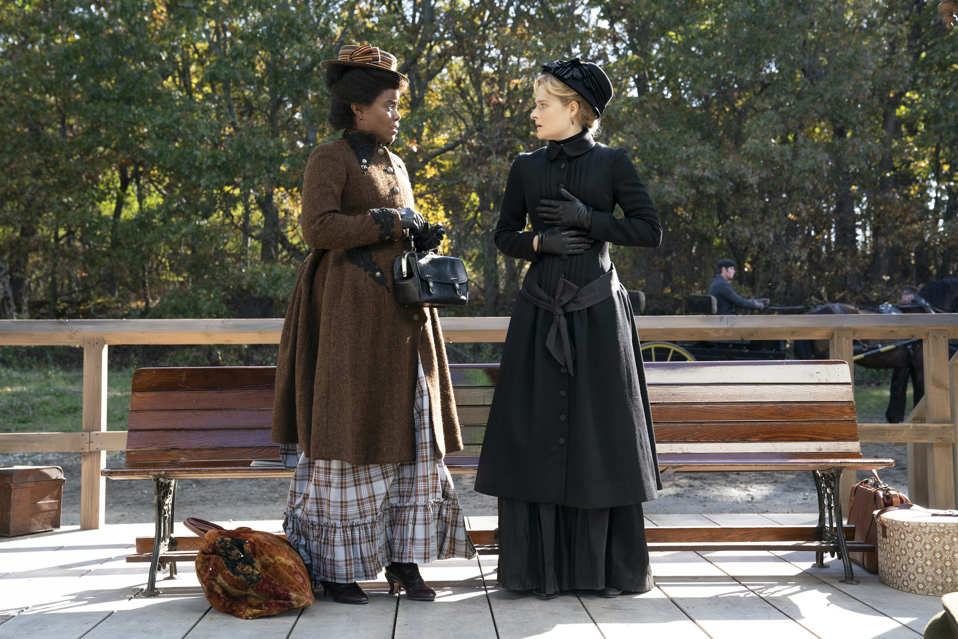 Two characters talking outside next to a bench in &quot;The Gilded Age&quot;