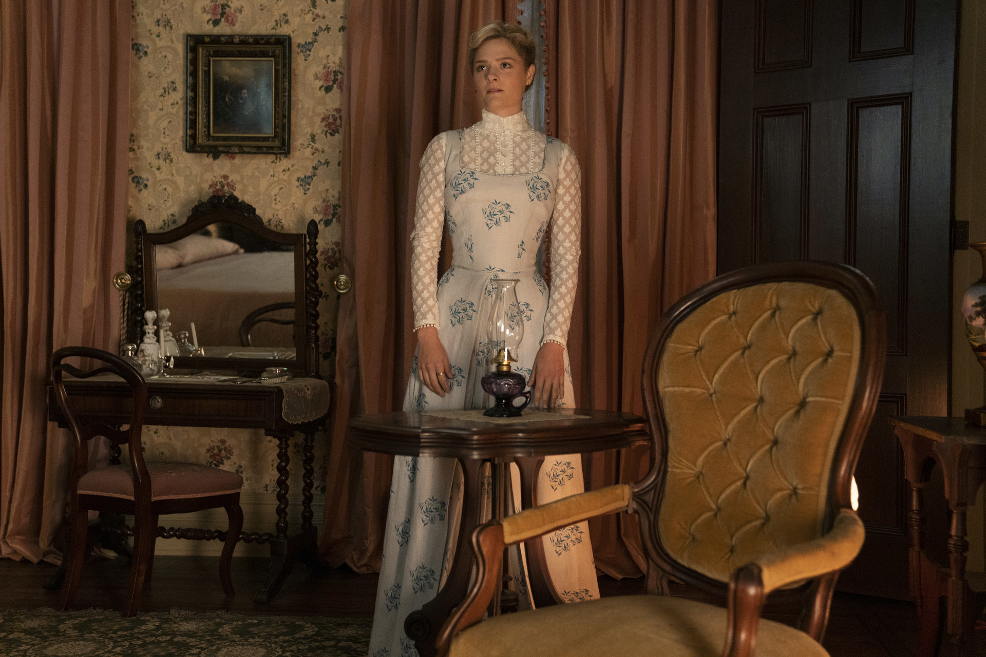 Louisa stands in front of an oil lamp in a room