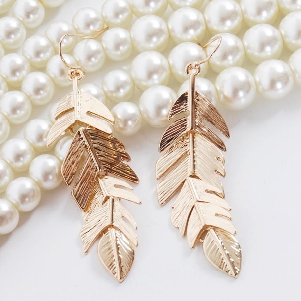 A pair of gold metal feather dangle earrings