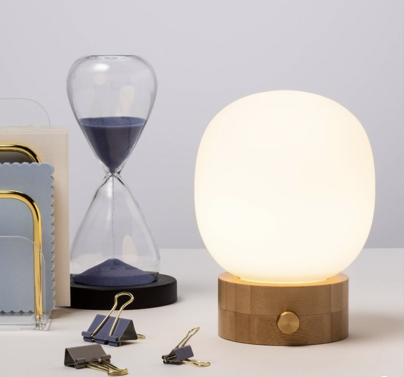 A modern table lamp with a frosted dome top and brass knob