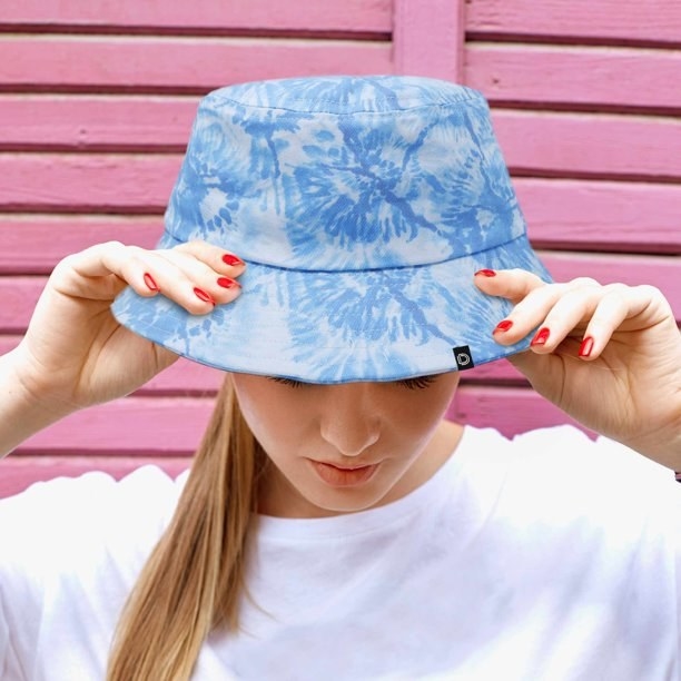 A model wearing a blue tie dye bucket hat