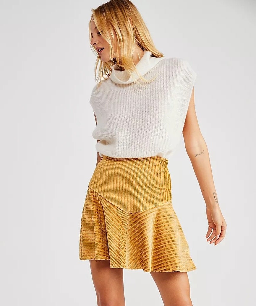 model wearing a white top and yellow mini skirt