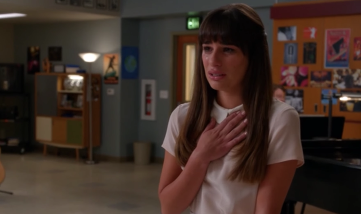 A close up of Rachel Berry as she stands with her hand over her heart while she cries