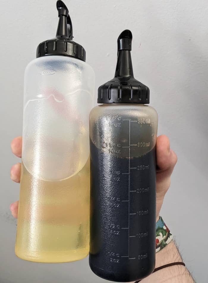 Someone holding two squeeze bottles, the larger one with oil in it and the smaller one with soy sauce