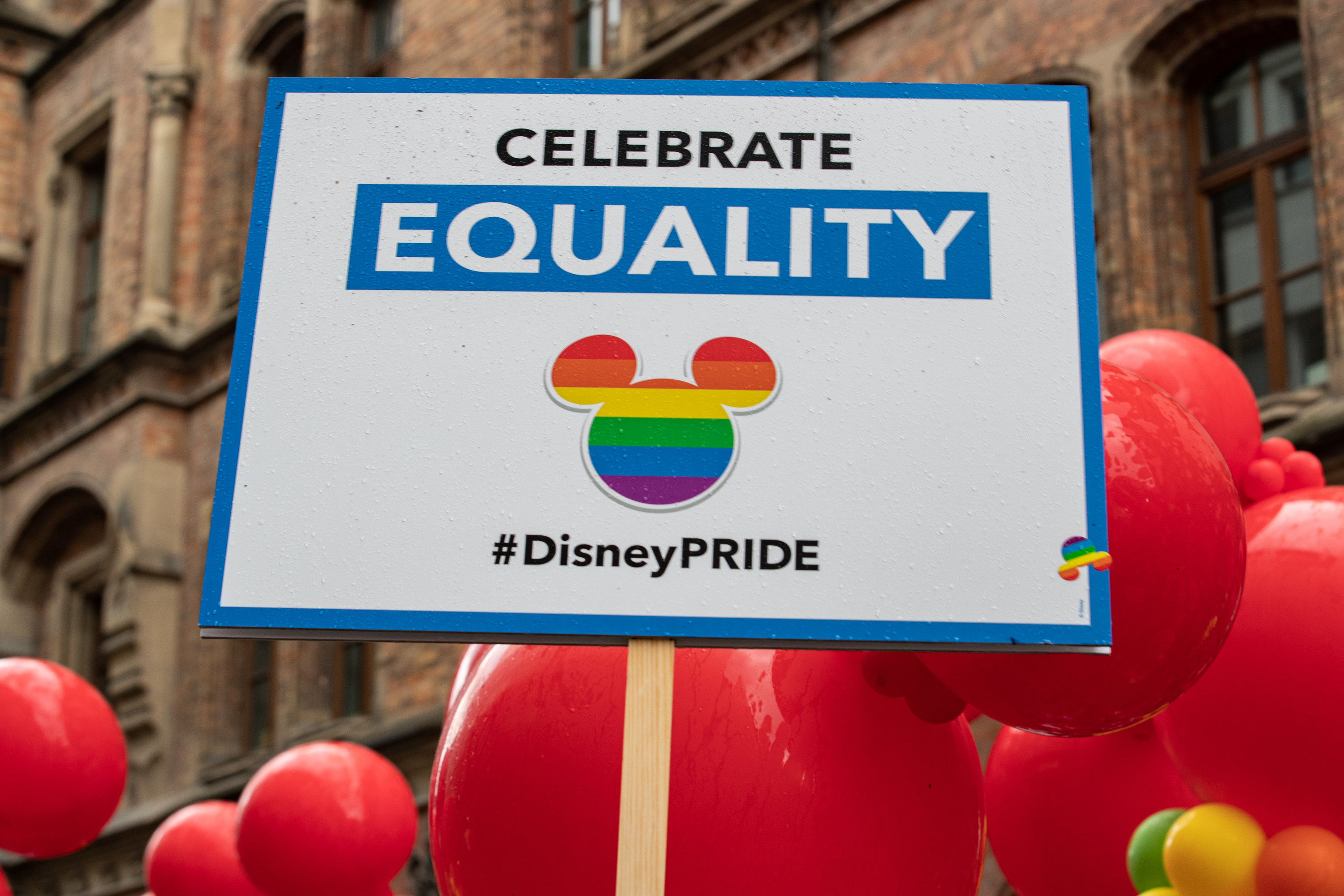 A sign that reads &quot;Celebrate Equality&quot; above a rainbow-colored Mickey Mouse head
