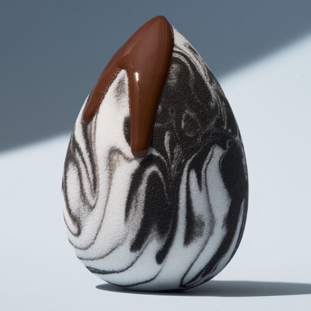 A black and white beauty sponge with foundation on it