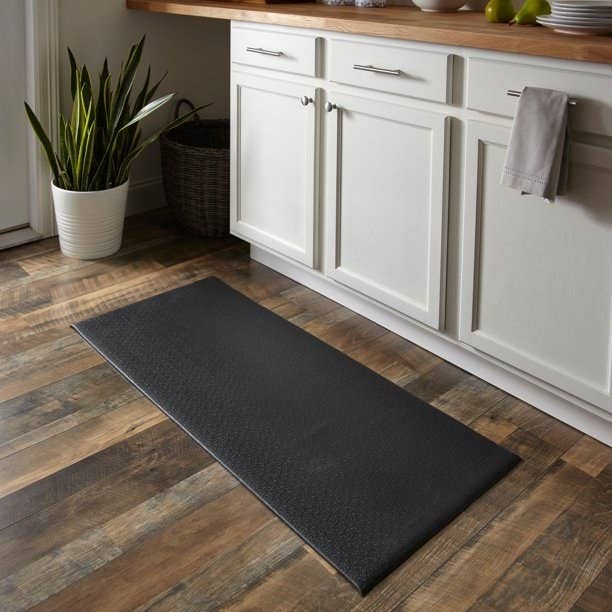 Black comfort mat on wooden floor in kitchen